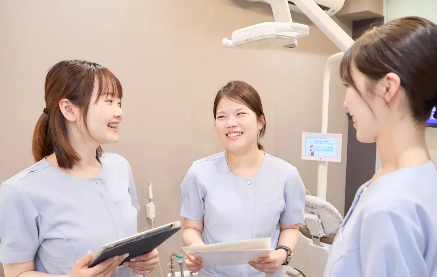 研修後、スタッフがノートを広げながら外部講師と笑顔で話している和やかなシーン。「学ぶ緊張感」と「温かいチームの雰囲気」のコントラストが伝わる。